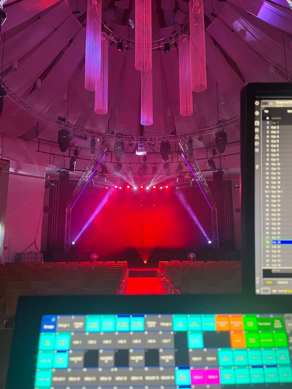 Lichtsteuerung mit farbigen Tasten vor einer rot ausgeleuchteten Bühne in einem Zeltsaal