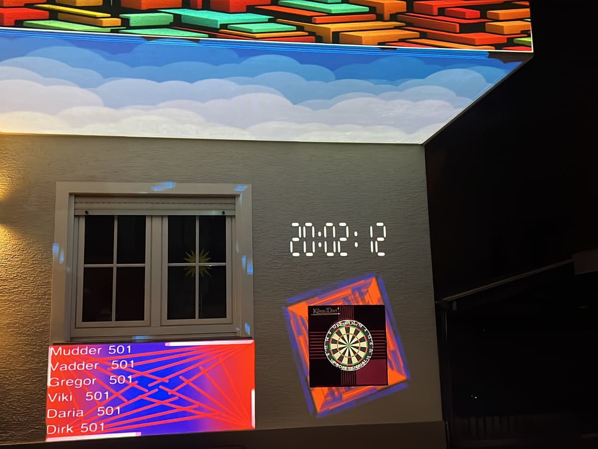 Raum mit farbiger Projektion an Decke und Wand, darunter eine projizierte Dart-Anzeige