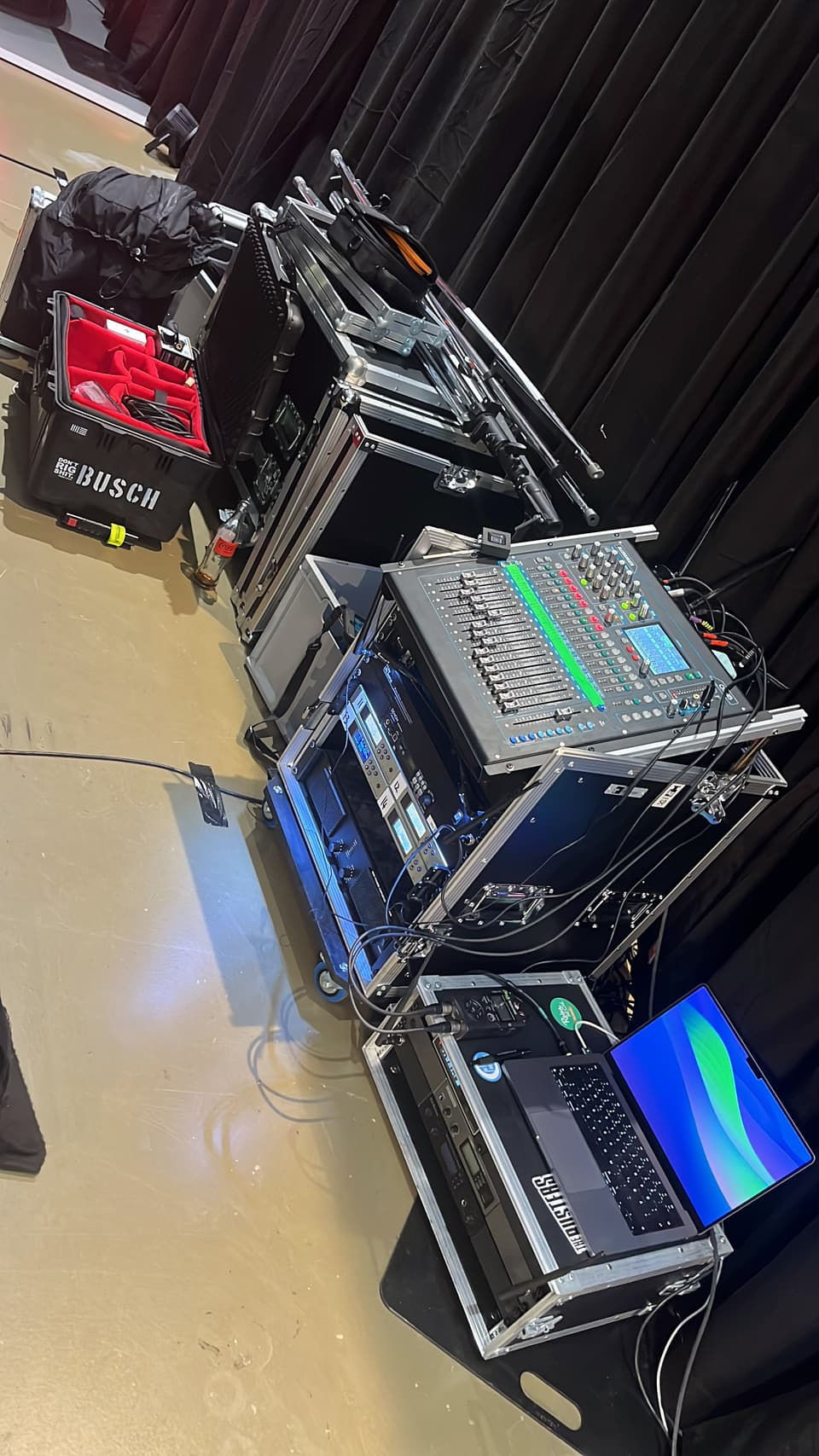 Aufgebaute Technik-Racks und Flightcases mit Mischpult und Laptop neben der Bühne