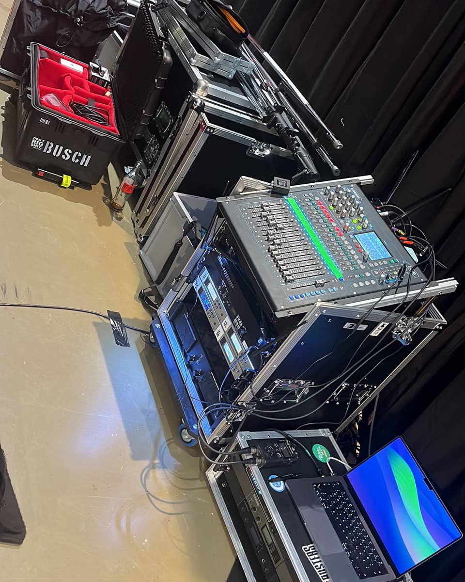 Technik-Racks und Flightcases mit Mischpult und Laptop neben der Bühne