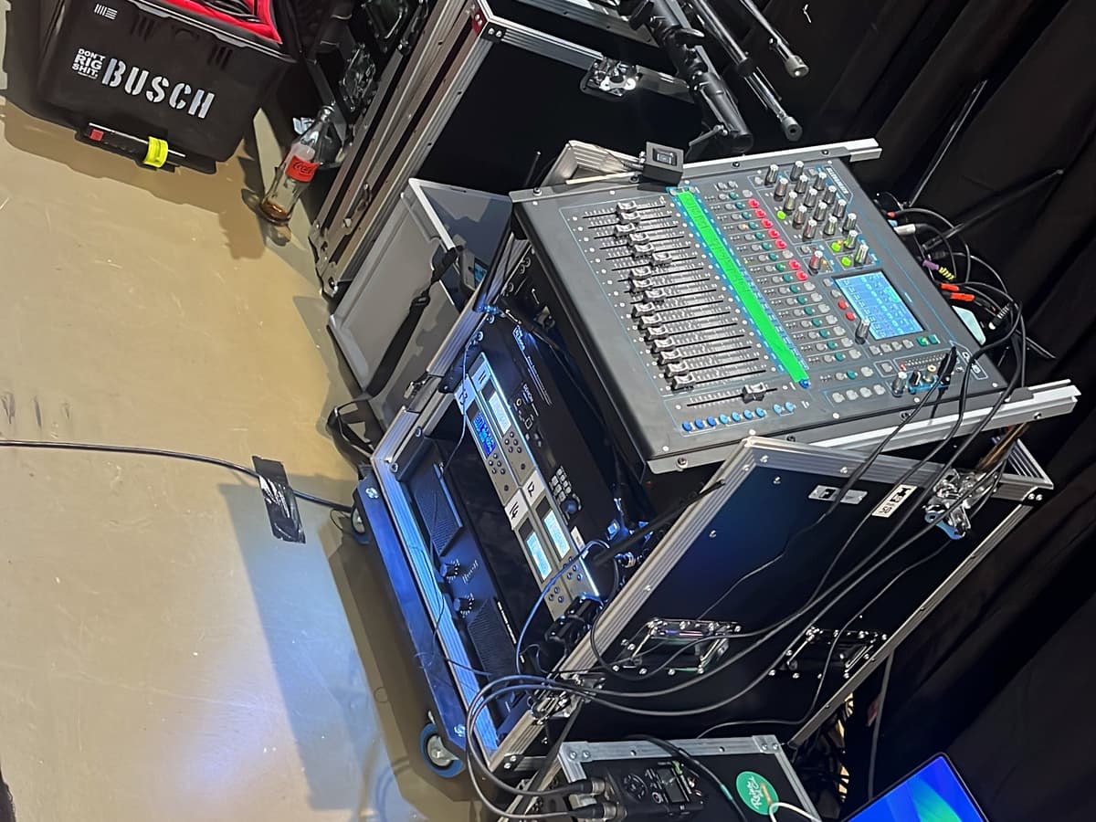 Technik-Racks und Flightcases mit Mischpult und Laptop neben der Bühne